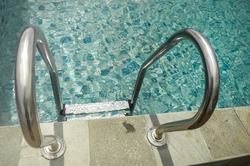Stainless-steel entrance ladder with handrail on a swimming pool