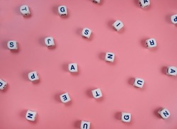  cubes or blocks word with letters randomly on a pink background - the concept of a newborn girl , school education or self education .