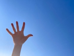 hand with beautiful clear blue sky in the background symbolizes a person that reaching a peace as high as the sky