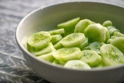 Fresh cucumber slices in a white bowl. Cucumbers in a dish and isolated on white background.