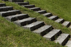 two parallel diagonal lines of stairs on a background of green grass 
