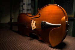 violin resting on its side from a perspective on a luthiers table 