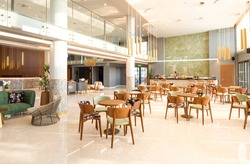Light wooden and marble tile floor interior of modern cafe with double ceiling height. Lobby bar in luxury design hotel hall with second split level
