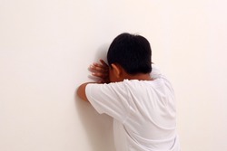 Asian boy playing hide and seek. Asian boy crying on the wall. Isolated on white.
