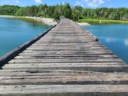 The top down view of the magnificent Old bridge at Summerville beach. The wooden planks are weathered and old. There's a barrier at the other side of the wooden roadway.