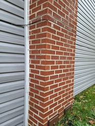 The side view of a large chimney. There is a new, white gutter running down alongside the chimney.