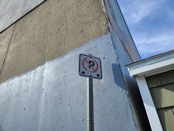 A no parking sign next to a building. The pictogram is the letter P with a circle around it that is crossed out.