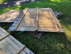A bunch of wooden fence paneling sitting on the ground as a fence is being constructed.