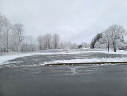 A large cleared parking lot of a winter dat with snow surrounding it.
