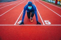 Runner wearing medical mask, Coronavirus pandemic Covid-19 in Europe. Sport, Active life in quarantine surgical sterilizing face mask protection. Outdoor run on athletics track in Corona Outbreak