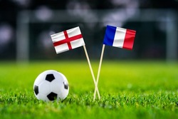 England - France. Quarter-finals football match. Round of 8. Handmade national flags and soccer ball on green grass. Football stadium in background. Black edit space.