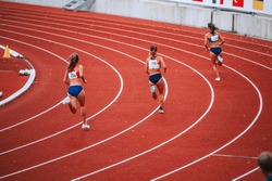 Female athletes at the starting line of a 400m race on track, showcasing their focus and determination as they prepare to compete