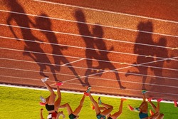 Female Athletes Shadows on Athletics Track in Sunset light. Legs of athletes, edit space. Photo for Worlds in Budapest and Games in Paris