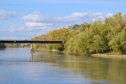 Bridge over the river. Autumn leaves on poplars along the river bank