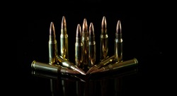 7.62mm ammunition cartridges standing and laid down on black background 