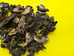 Bunch of dried wood ear mushrooms on yellow background with copy space