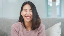 Teenager Asian woman feeling happy smiling and looking to camera while relax in living room at home. 