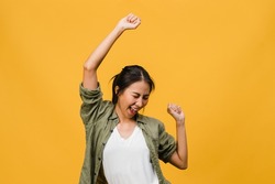 Young Asia lady with positive expression, joyful and exciting, dressed in casual cloth over yellow background with empty space. Happy adorable glad woman rejoices success. Facial expression concept.