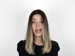 Young woman sticking out tounge, close up portrait. Teasing you through camera while isolated with white background. It looks like she doesn’t have arms.