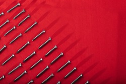 Black steel nails, arranged horizontally, leaving a diagonal space for advertising, on red cloth background
