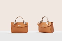 Beautiful brown leather female fashion handbags isolated on light beige background, front view