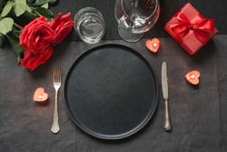 Valentine's day or birthday romantic dinner. Elegance table setting with red rose on black linen tablecloth.