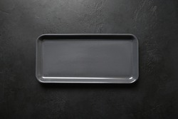 Empty black modern rectangular plate on black background. View from above. Copy space. Kitchen stuff, flat lay for cooking as background.