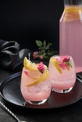 Alcoholic cocktails with pink rose gin and lemon on black background. Refreshing lemonade for festive party. Vertical format.