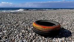 A car tire dumped on the beach.