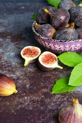 fresh ripe figs on dark table. Healthy Mediterranean fig fruit. Fresh figs on a dark background. Beautiful blue violet figs with leaves, copy space