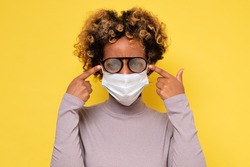 Cute african american woman with foggy glasses caused by wearing a COVID protective mask