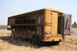 an old burnt out bus stands in a field