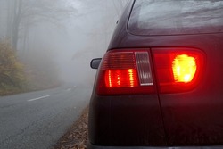 the back car light, rear fog and brake lights on the car on the early foggy. morning. bad conditions for driving