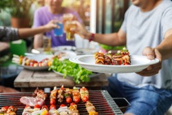 A man with a barbecue plate at a party between friends. Food, people and family time concept.