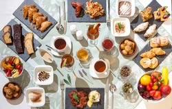 Impressive breakfast set up on a clothed table with traditional Mediterranean delicacies served on plates and plateau with coffee, tea, juices and marmalade.