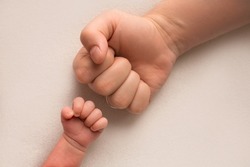 Dad and newborn boy son keep their hands in a fist, small and big fists. Father and son, the first boxing punch.