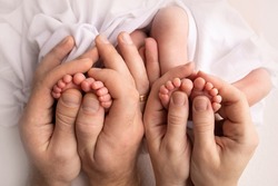Feet of newborn twins. Two pairs of baby feet. Parents, father mother hold newborn twins by the legs. Close up - toes, heels and feet of a newborn. Newborn brothers, sisters.