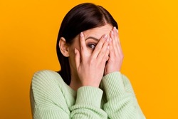 Photo of young girl cover face hands look eye spy scared frightened isolated over yellow color background.