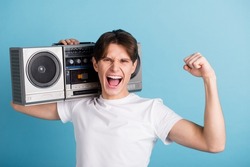 Photo of nice glad guy hold boom box dance fist up wear t-shirt isolated blue color background.