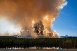 A forest wildfire has occurred in Yukon Territory, Canada, generating smoke that fills the sky and even obscures the sunshine.