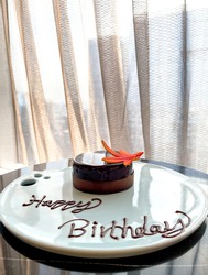 Delicious Birthday Chocolate Cake with words ‘Happy Birthday’ written in chocolate, perched on table by window with curtains closed