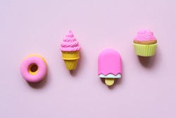 Different toy sweets in miniature with shadows close-up on a soft pink color background.