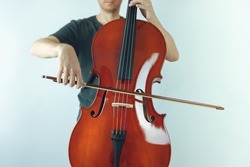 Playing with a bow on a mahogany cello.