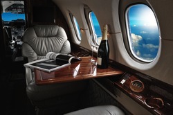 luxury interior in the modern  business jet and sunlight at the window/sky and clouds through the porthole