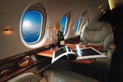 luxury interior in the modern  business jet and sunlight at the window/sky and clouds through the porthole