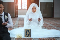 Islamic wedding ceremony at mosque. Bride and groom sitting in mosque at a Muslim wedding ceremony. Muslim bride and groom praying at the mosque during a wedding ceremony.