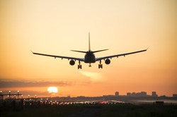 Airplane is landing during sunrise.