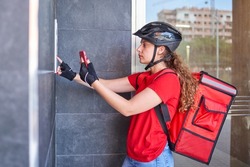 A cyclist delivery girl ringing the intercom bell