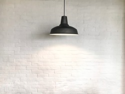 Black fixture of lamp have white bricks wall is background.