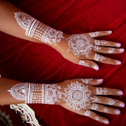 White bridal henna tattoos on two hands on red background. Moroccan wedding preparation henna party. Temperate white mehndi. Modern mehendi art.